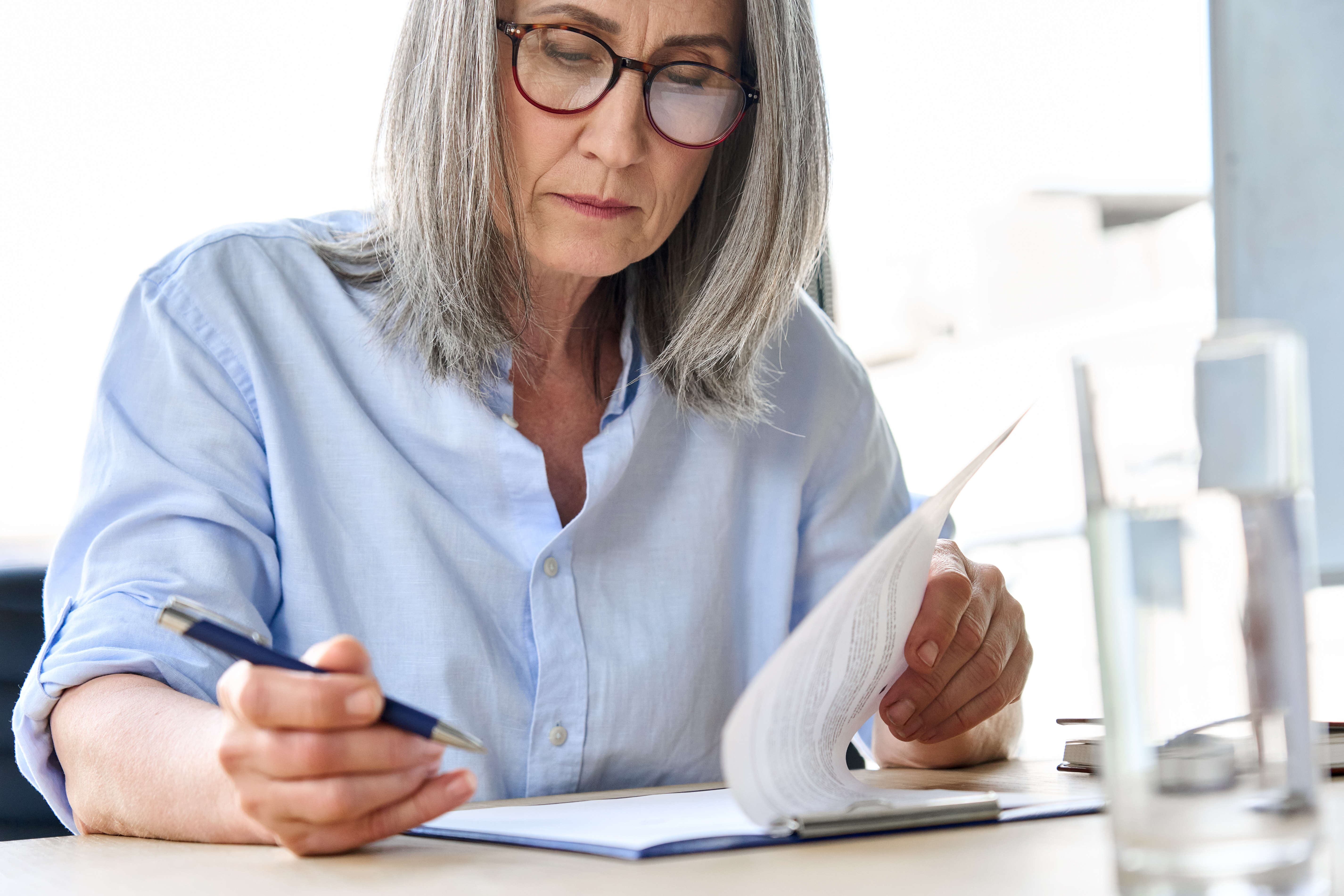 Woman in her 60s signing documents. These represent legal proceedings your elderly parent will encounter.