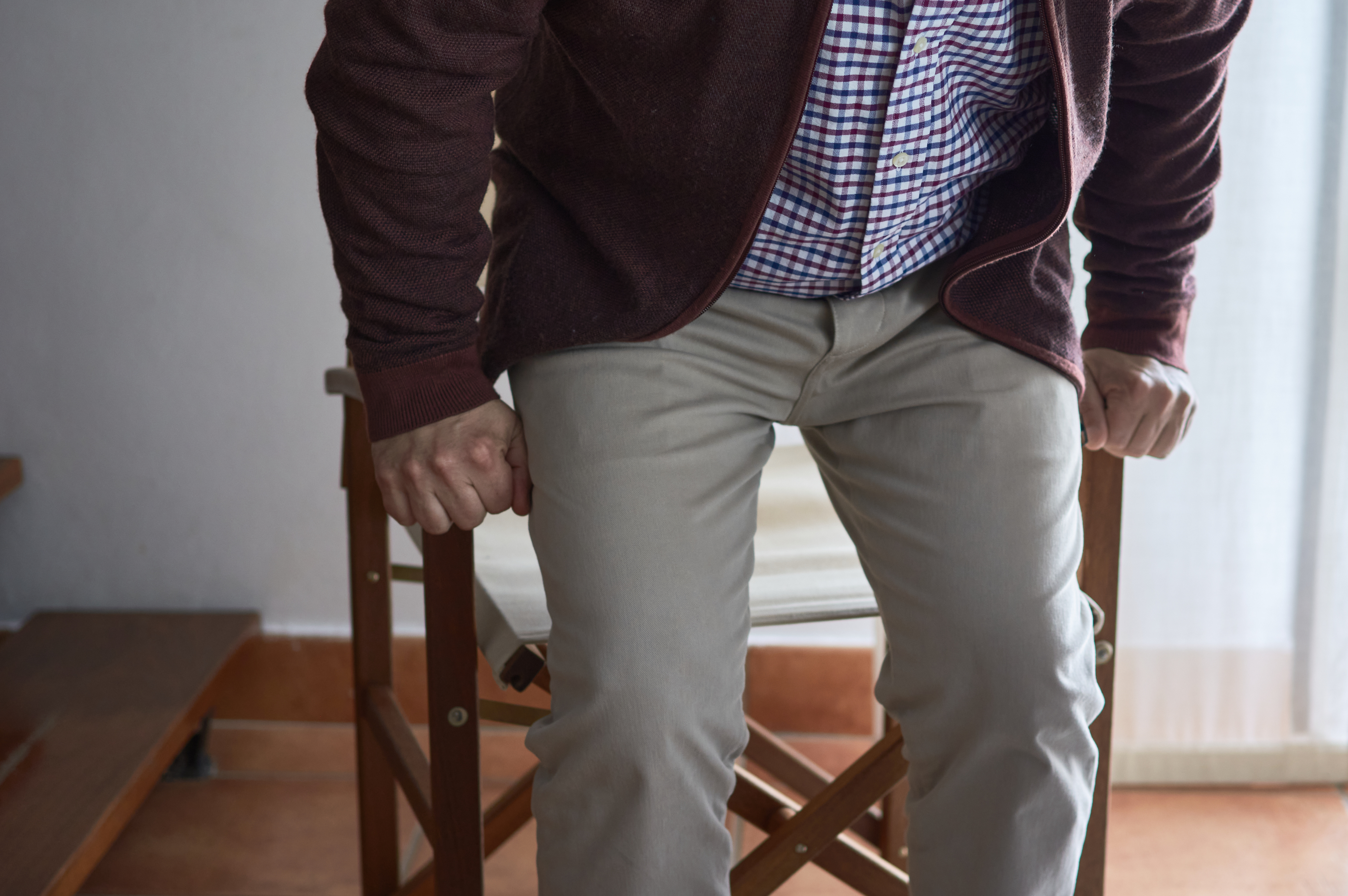 Older adult standing up from a chair, hands gripping the armrests for support – a common scenario for using fall sensor pads to detect instability and help prevent accidents at home.