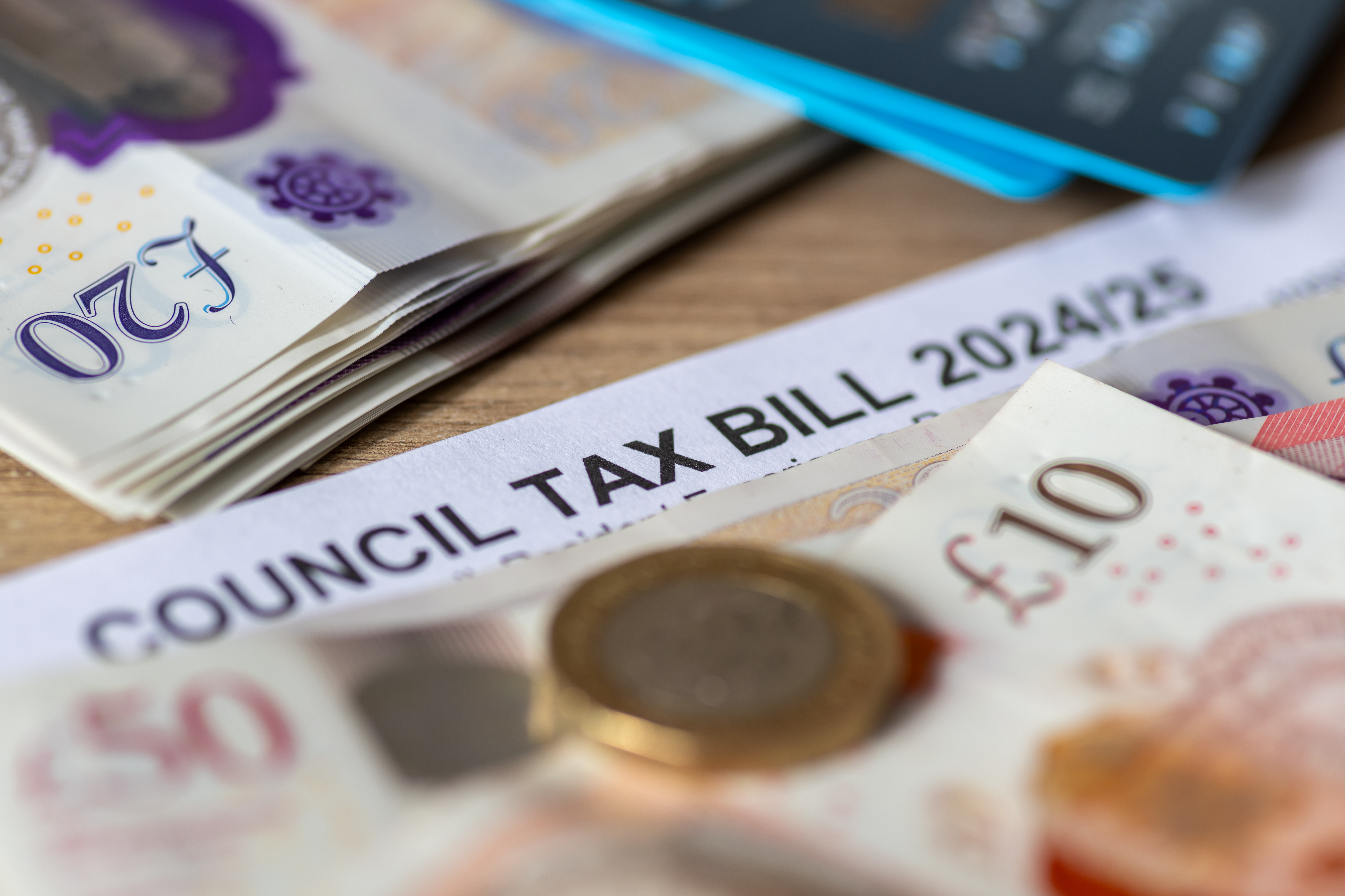 A close-up of a UK council tax bill for 2024/25, with twenty-pound notes and coins. A representation of financial planning, tax reductions, and support schemes for carers and elderly parents.