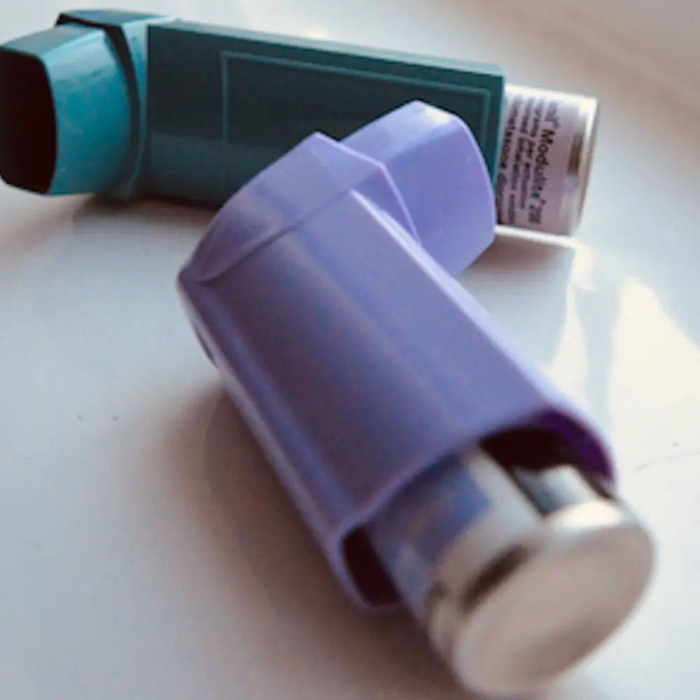 Two inhalers on a surface - one is blue, the other purple