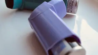 Two inhalers on a surface - one is blue, the other purple