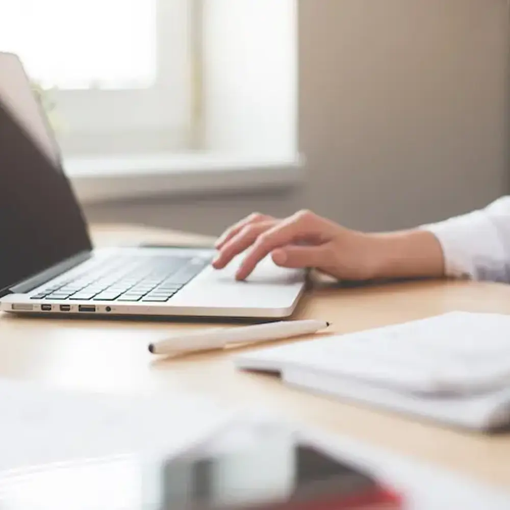 Woman sitting at a laptop with items strewn across the desk