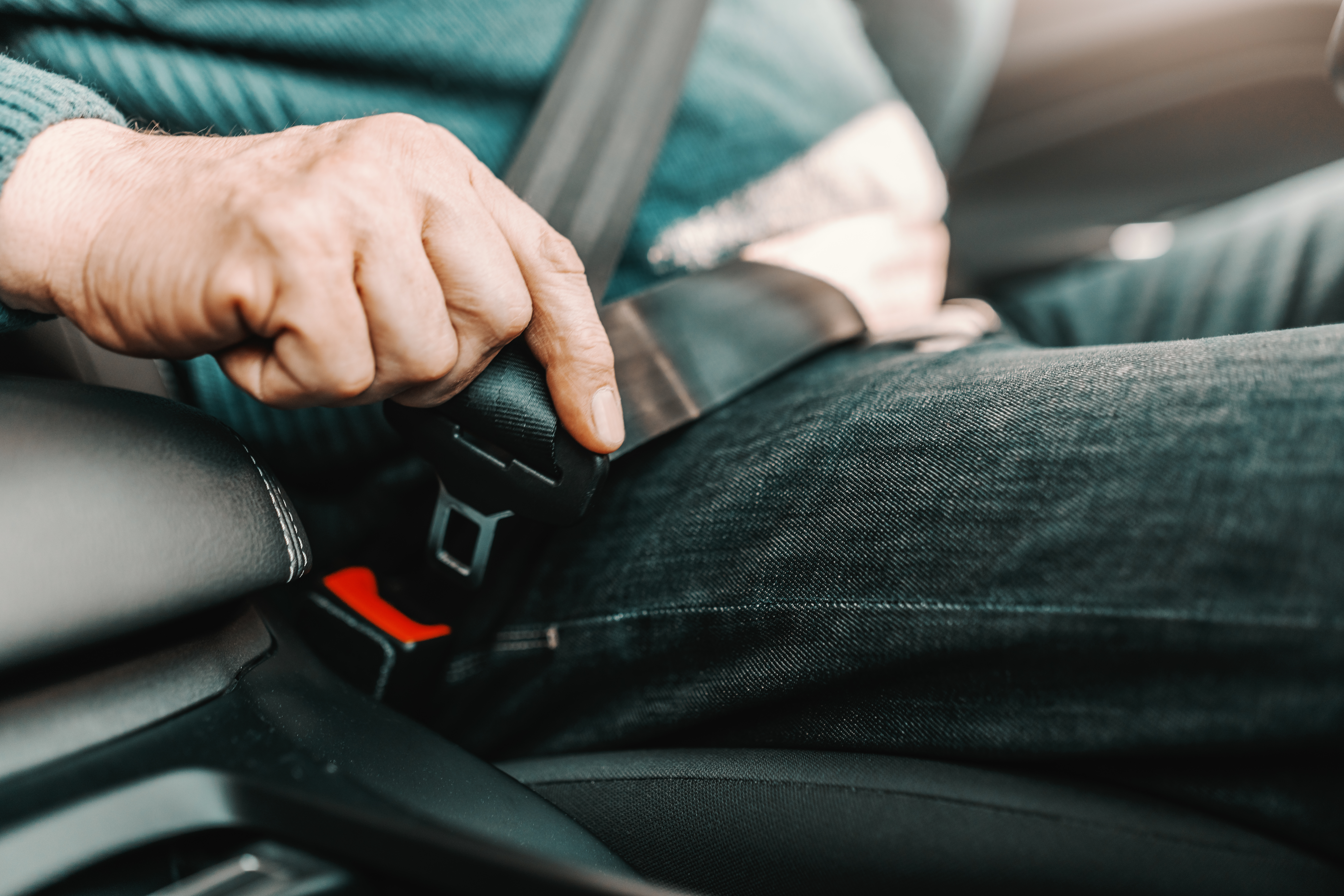 Older adult fastening a car seat belt – seat belt assists help elderly parents with limited reach or grip strength buckle up more easily and safely when getting into a vehicle.