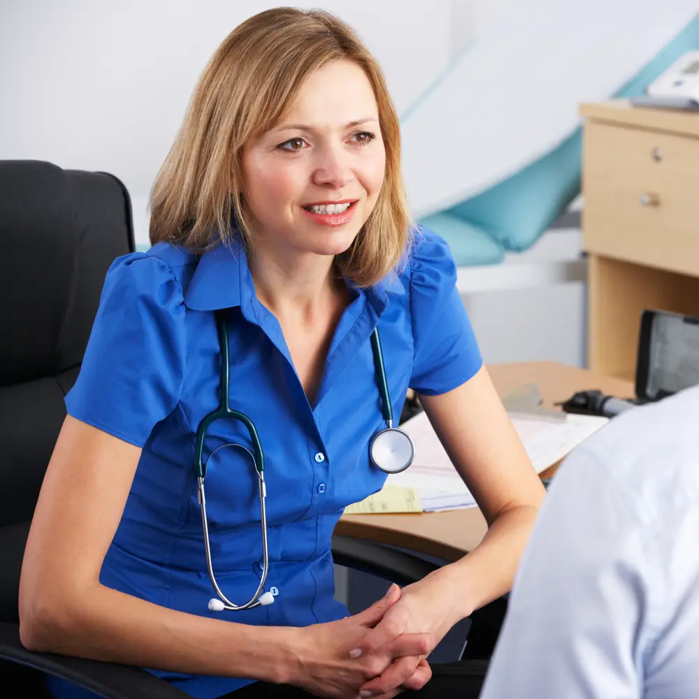 Consulting a GP About Elderly Parent’s Health – A female doctor in a blue uniform listens attentively to a patient. A reminder of the importance of regular check-ups and seeking professional medical advice for elderly loved ones.