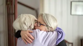 A middle aged woman hugging her elderly parent