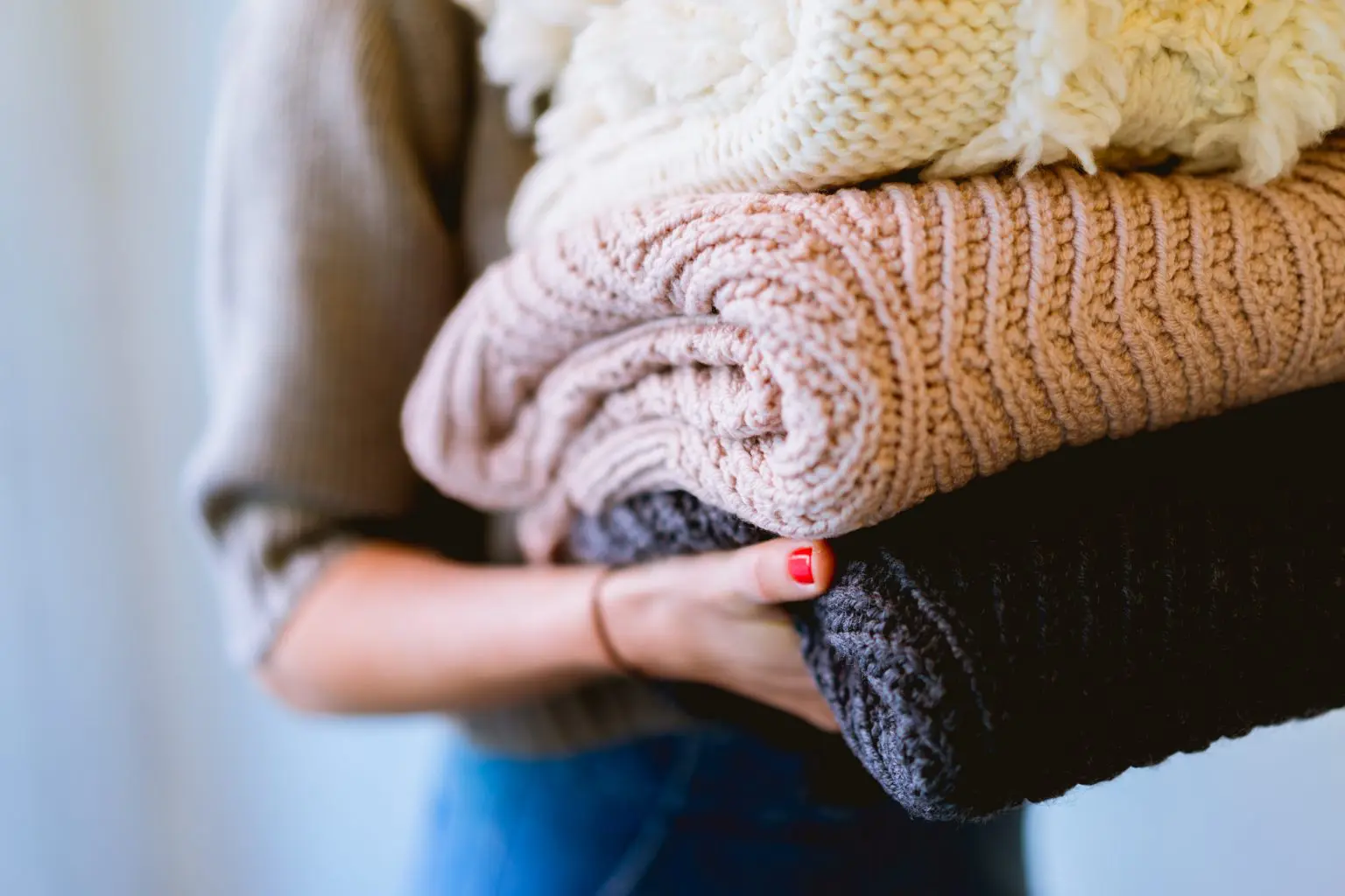 A woman carrying blankets of three shades of colours - white, pink and navy