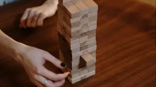 Wooden Jenga blocks with a middle aged woman taking out a piece