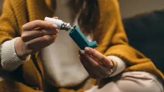 woman sitting down and looking at an inhaler