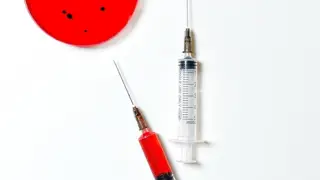 Image of a virus in a petri dish with two syringes lying next to it