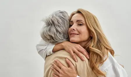 A picture of a woman and her elderly mother, both smiling at the camera. The woman cares for her elderly parent and has written a letter to her