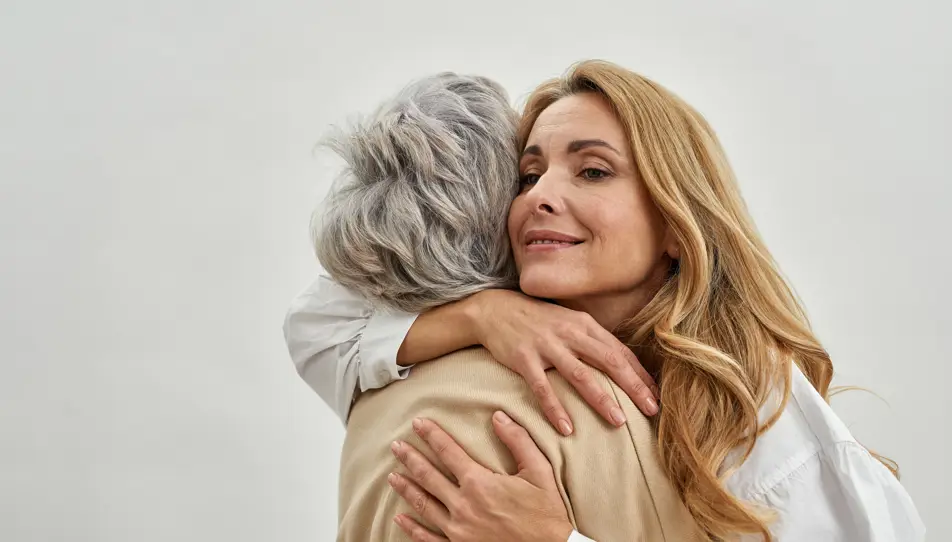 A picture of a woman and her elderly mother, both smiling at the camera. The woman cares for her elderly parent and has written a letter to her